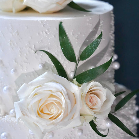 Elegante Hochzeitstorte mit Perlen und weißen Rosen