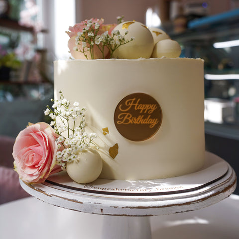 Torte mit frischen Blumen und Schokokugeln